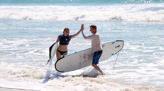 Friends high-fiving after a surf lesson at Playa La Lancha