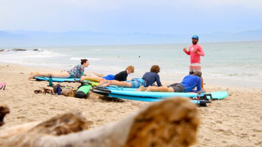 Family receiving surf instructions from WildMex coach during land lesson at Playa La Lancha