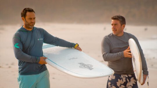 Two friends walking toward the ocean with surfboards at Playa La Lancha