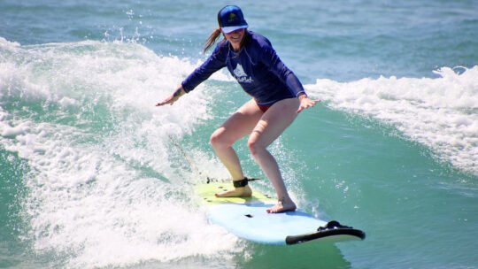 Smiling girl surfing a wave at Playa La Lancha in Punta Mita