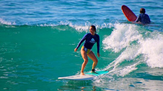 Smiling woman surfing a wave at La Lancha beach near Puerto Vallarta