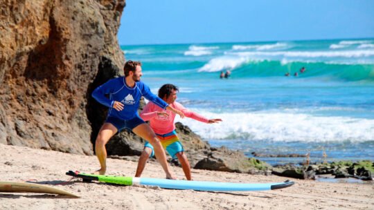 Surfer receiving land-based instruction from WildMex coach before entering the water