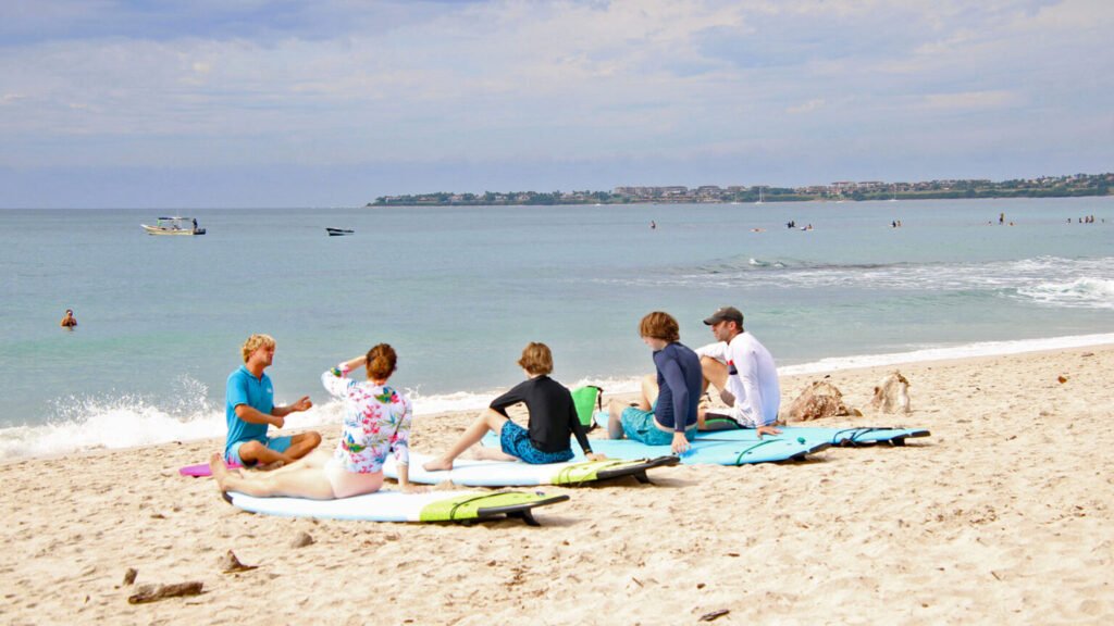 Family receiving land surf lesson from instructor before entering water in Punta Mita