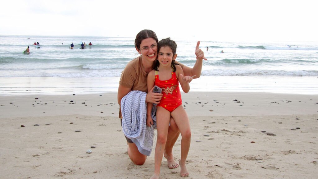 Mother and daughter smiling and making Shaka sign after surf lesson in La Lancha Beach