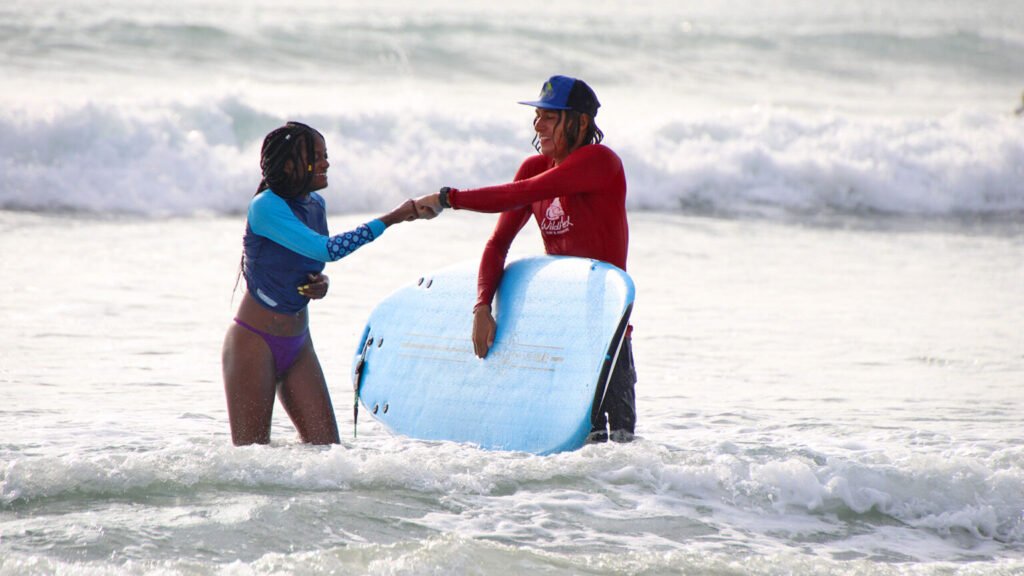Female surfer fist-bumping instructor after successful surf lesson in Sayulita