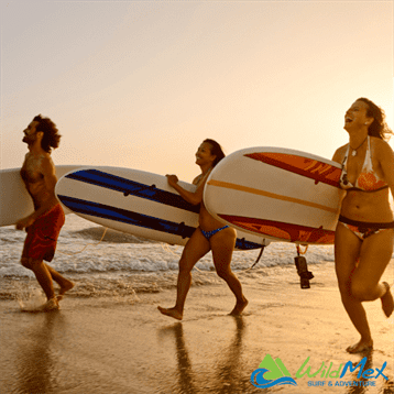 Surfers running on a beach with surfboards at sunset Surfers running on a beach with surfboards at sunset