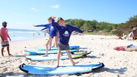 Happy boy on his surfboard during land lesson in La Lancha