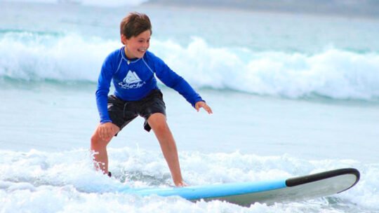 isa-certified coach helping child pop-up during kids surf lessons in sayulita