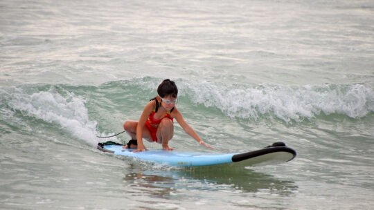 Focused girl riding a wave during her surf lesson in La Lancha