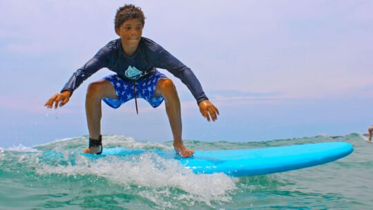 Joyful boy balancing on a wave during his surf lesson in Punta Mita