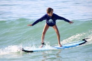 Young girl surfing during her first lesson, captured in a surf photo session