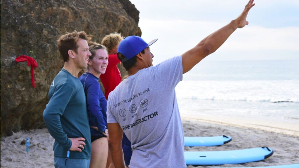 Surf instructor briefing couple on beach conditions at Sayulita before surf session