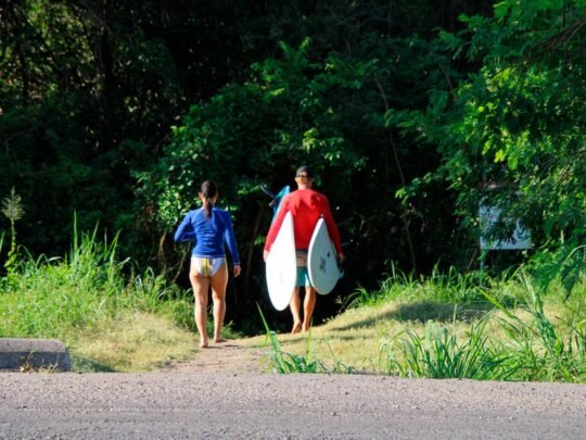 Surfer and WildMex instructor walking through the jungle trail to La Lancha surf break in Punta Mita
