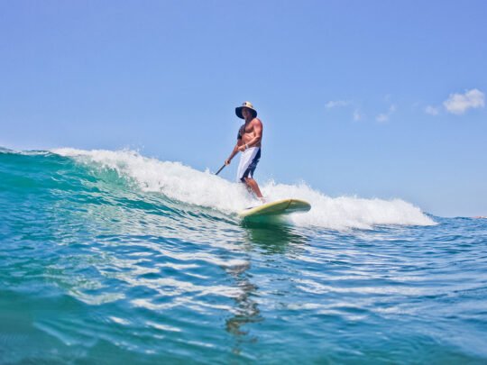 Man catching a small wave on paddle board in Punta Mita